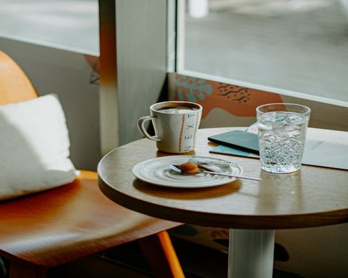 A glass of water next to a vintage notebook on a wooden table during early morning hours